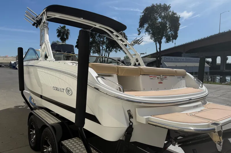 Slide: The Image of 2016 Cobalt 220 boat on trailer, dockside with trees and bridge in background. - 4