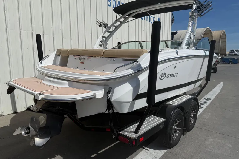 Slide: The Image of 2016 Cobalt 220 boat on trailer, white exterior, parked near a building. - 6