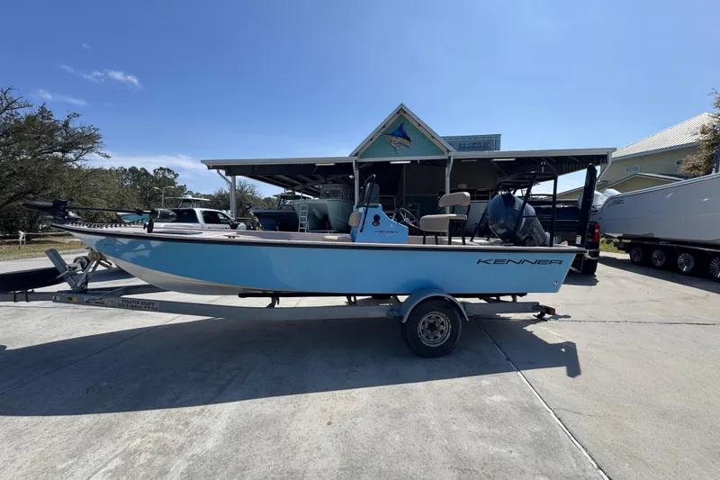 The Image of 2004 Kenner 21 VX boat on trailer, parked outdoors under clear blue sky. - 1