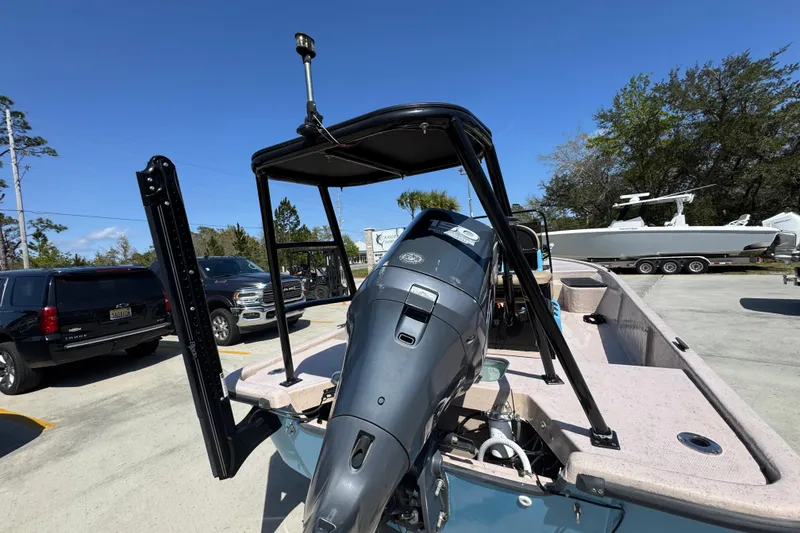 Slide: The Image of 2004 Kenner 21 VX boat with outboard motor, parked outdoors under clear blue sky. - 13