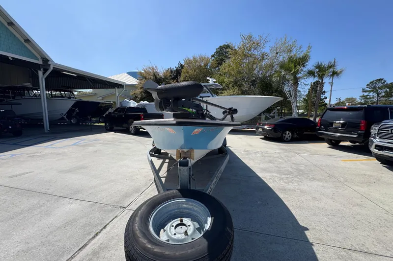 Slide: The Image of 2004 Kenner 21 VX boat on trailer in parking lot, surrounded by vehicles and trees. - 5