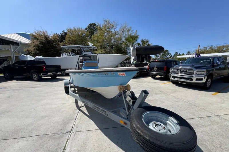Slide: The Image of 2004 Kenner 21 VX boat on trailer in parking lot, surrounded by trucks. - 6