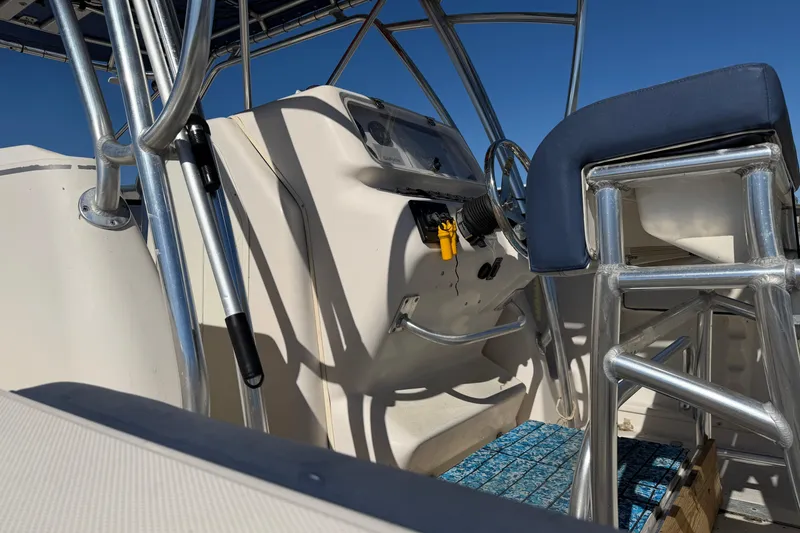 Slide: The Image of 2007 Cobia 312 Sport Cabin helm with steering wheel and seating under clear blue sky. - 22