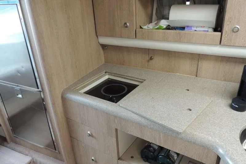 Slide: The Image of Compact kitchen area in a 2001 Formula 400 Super Sport boat, featuring a stove and storage. - 25