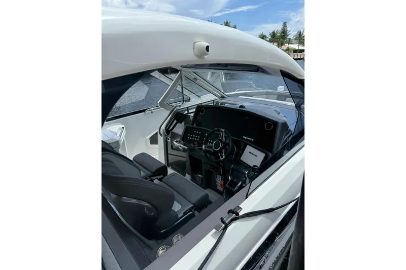 Slide: The Image of 2024 Galeon 325 GTO cockpit with modern steering and navigation controls, docked by the water. - 3