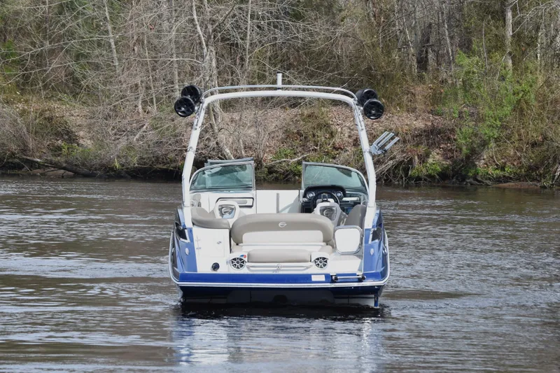 Slide: The Image of 2019 Crownline Eclipse E255 SURF boat on a calm river, surrounded by trees. - 2
