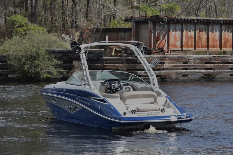 Slide: The Image of 2019 Crownline Eclipse E255 SURF boat on a calm river near a rustic dock. - 3