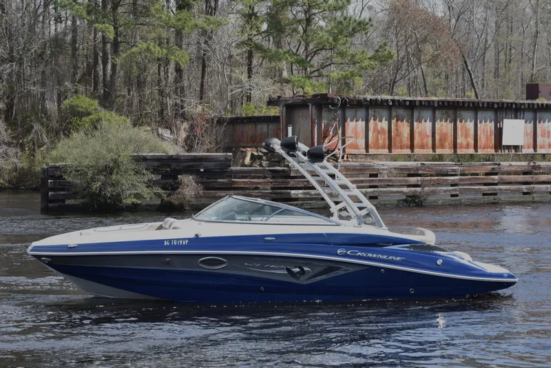 Slide: The Image of 2019 Crownline Eclipse E255 SURF boat on a calm river near a wooded shoreline. - 4