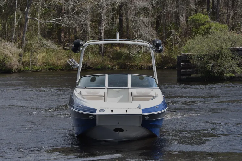 Slide: The Image of 2019 Crownline Eclipse E255 SURF boat on a river, surrounded by trees. - 5