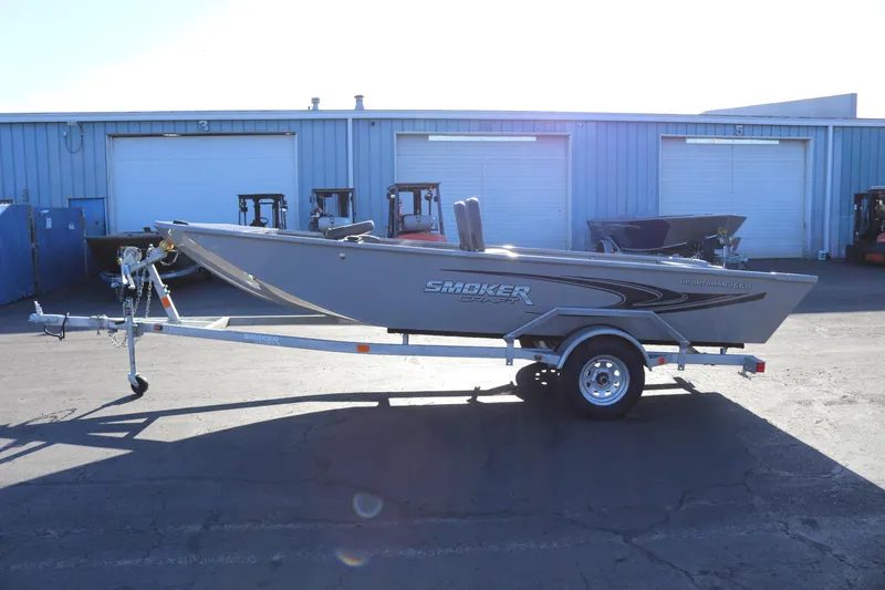 The Image of 2026 Smoker Craft Pro Sportsman 1660 boat on trailer, parked outside industrial building. - 0