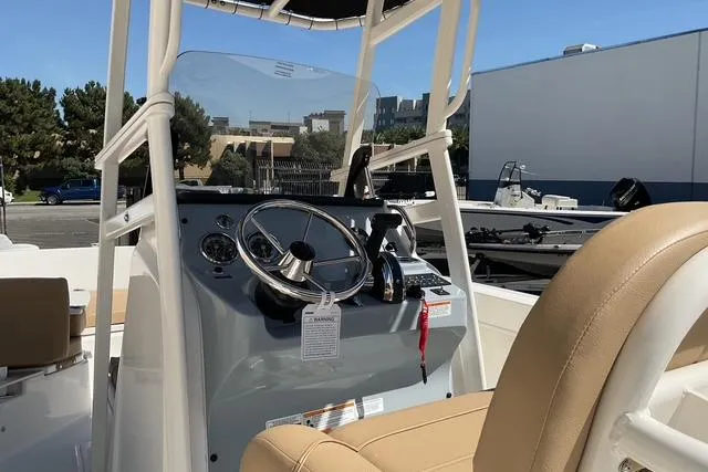 Slide: The Image of 2026 Bayliner Trophy T22CC boat cockpit with steering wheel and beige seating. - 6