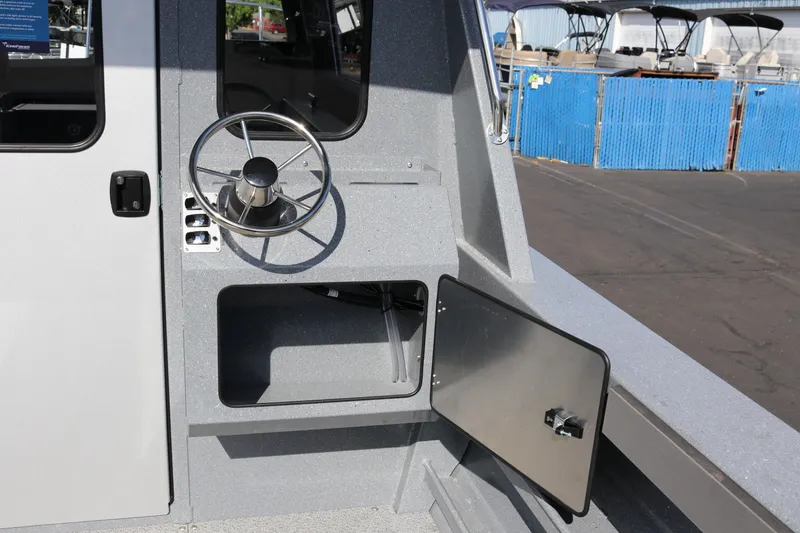 Slide: The Image of 2026 KingFisher 2825 Coastal Express boat helm with steering wheel and storage compartment. - 10