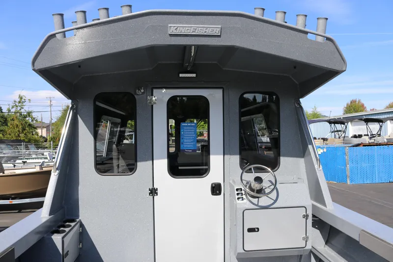 Slide: The Image of 2026 KingFisher 2825 Coastal Express boat exterior with steering wheel and cabin door. - 9