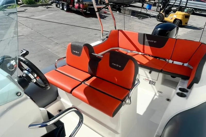 Slide: The Image of 2024 Zodiac Medline 6.8 boat interior with vibrant orange seating and steering wheel. - 12