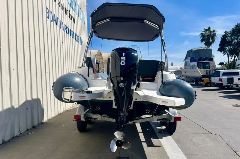 Slide: The Image of 2024 Zodiac Medline 6.8 boat with 150 HP engine, parked outdoors. - 6