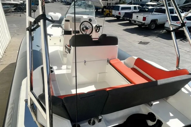 Slide: The Image of 2024 Zodiac Medline 6.8 boat interior with seating and steering wheel in a marina. - 8