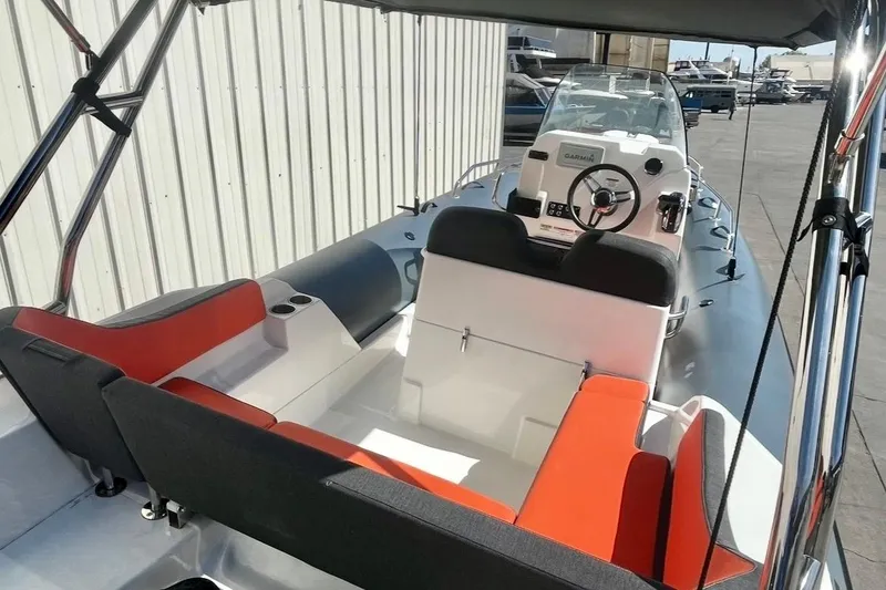 Slide: The Image of 2024 Zodiac Medline 6.8 boat interior with red and black seating, steering console, and canopy. - 9