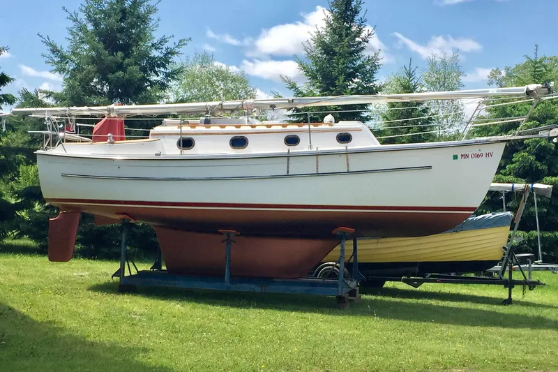 Slide: The Image of 1997 Com Pac 27-2 sailboat on trailer, surrounded by trees under a blue sky. - 10