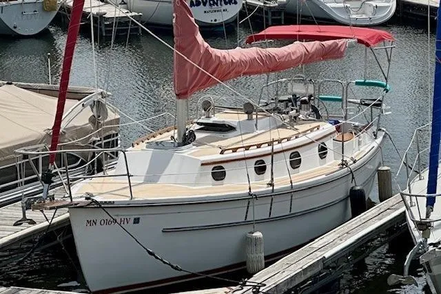 Slide: The Image of 1997 Com Pac 27-2 sailboat docked in marina with red sail cover. - 11