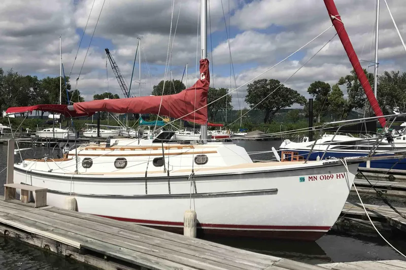 Slide: The Image of 1997 Com Pac 27-2 sailboat docked at a marina with red sail cover. - 12