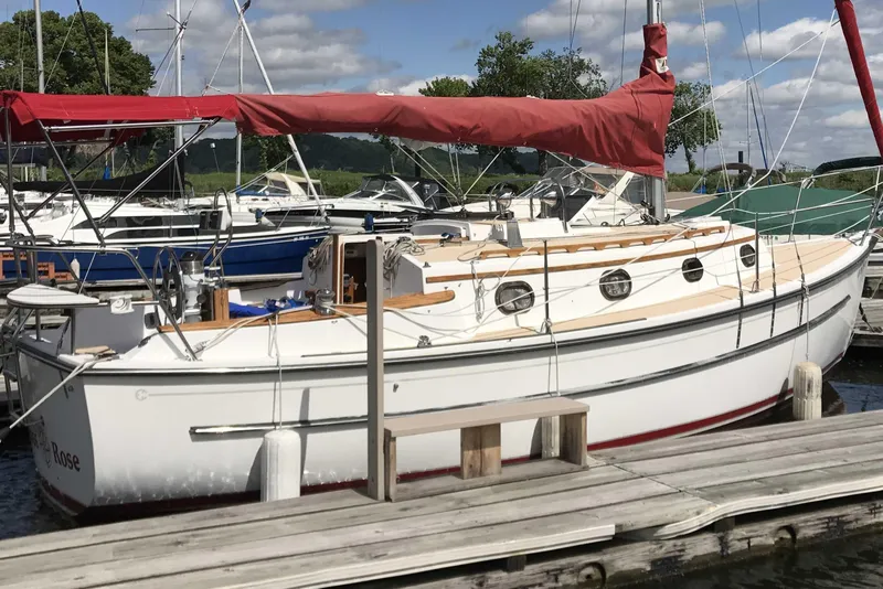 Slide: The Image of 1997 Com Pac 27-2 sailboat docked at a marina with red sail cover. - 13