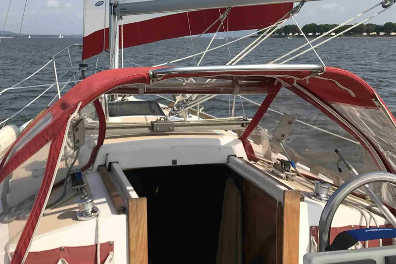 Slide: The Image of 1997 Com Pac 27-2 sailboat cockpit with red canopy on open water. - 3