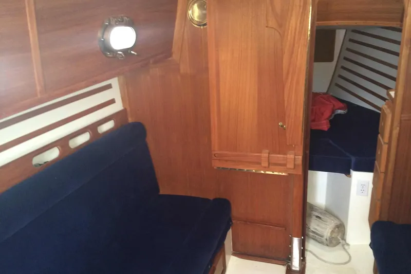 Slide: The Image of Interior of a 1997 Com Pac 27-2 sailboat with wooden paneling and blue seating. - 5
