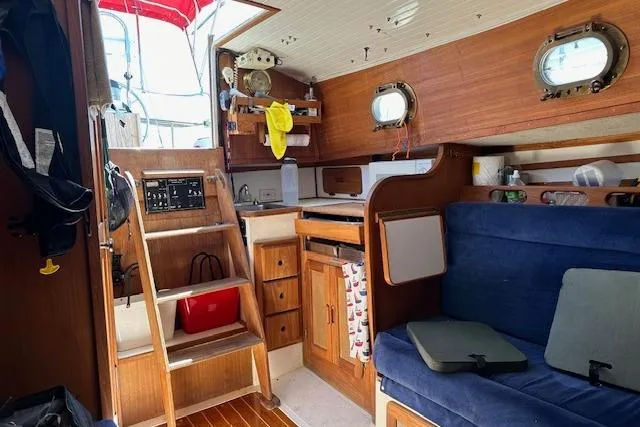 Slide: The Image of Interior of a 1997 Com Pac 27-2 sailboat with wooden cabinetry and blue seating. - 8