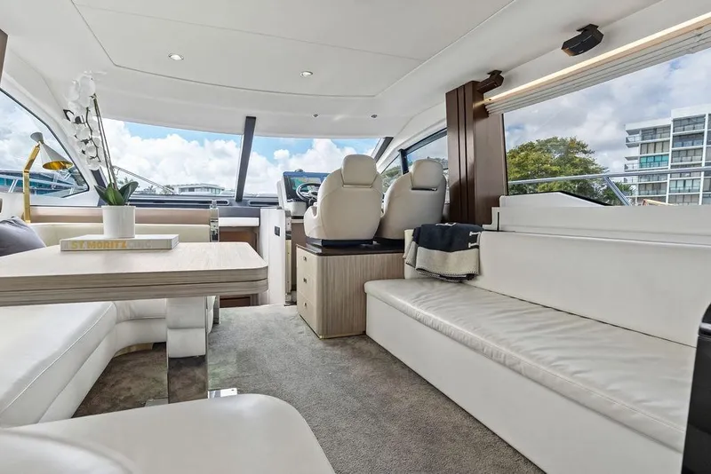Slide: The Image of Luxurious 2019 Azimut yacht interior with modern seating, table, and helm, featuring panoramic windows. - 22