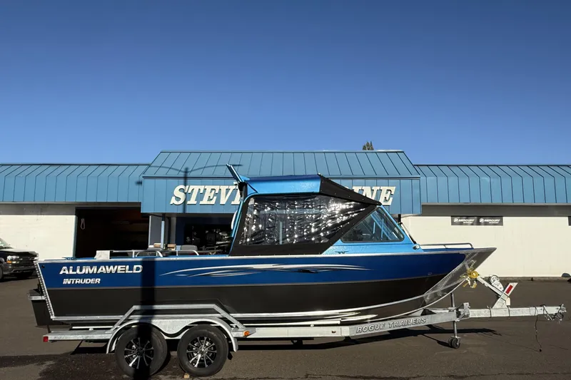 The Image of 2026 Alumaweld Intruder Outboard 22 boat on trailer, parked outside marine store. - 1