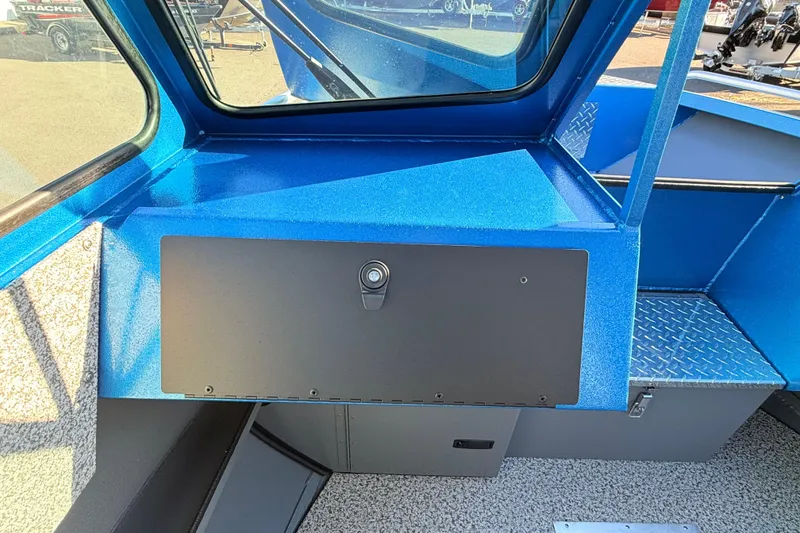 Slide: The Image of Interior view of 2026 Alumaweld Intruder Outboard 22 boat, featuring blue dashboard and storage compartment. - 29