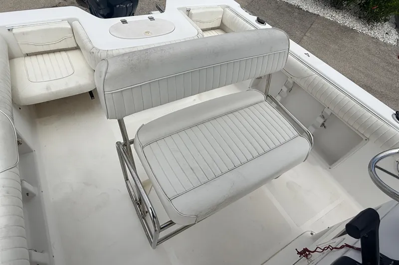 Slide: The Image of 2007 Sea Hunt Triton 220 boat interior with white cushioned seating and steering area. - 10