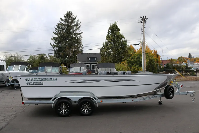 The Image of 2026 Alumaweld Columbia 23 boat on trailer, parked outdoors with trees in background. - 1