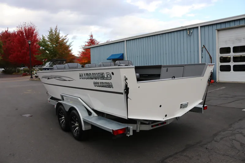 Slide: The Image of 2026 Alumaweld Columbia 23 boat on trailer, parked near blue building, autumn trees in background. - 3