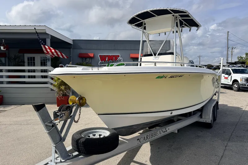 Slide: The Image of 2006 Sea Hunt Triton 220 boat on trailer, parked outside dealership with American flag. - 2