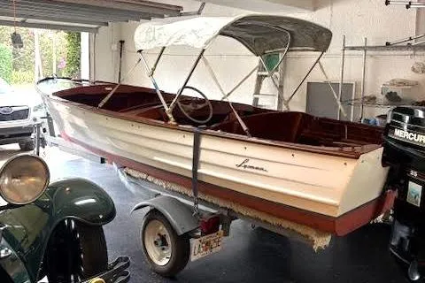 The Image of 1952 Lyman 15 Classic Runabout boat in garage, on trailer, with canopy. - 0