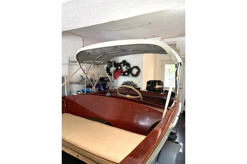 Slide: The Image of 1952 Lyman 15 Classic Runabout boat with canopy in a garage setting. - 2