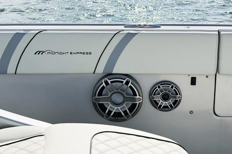 Slide: The Image of Midnight Express 43 Open boat interior with speakers and logo, on water background. - 11