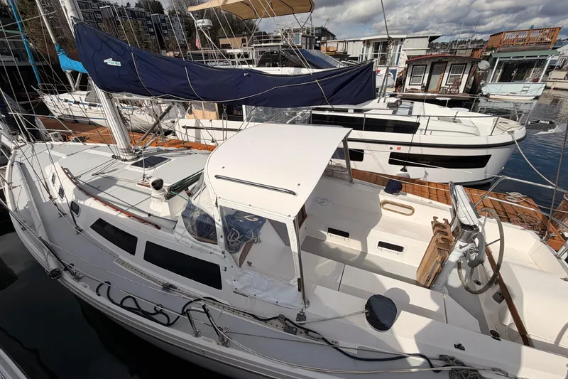 Slide: The Image of 1989 Catalina 34 sailboat docked at marina, featuring white deck and blue sail cover. - 19