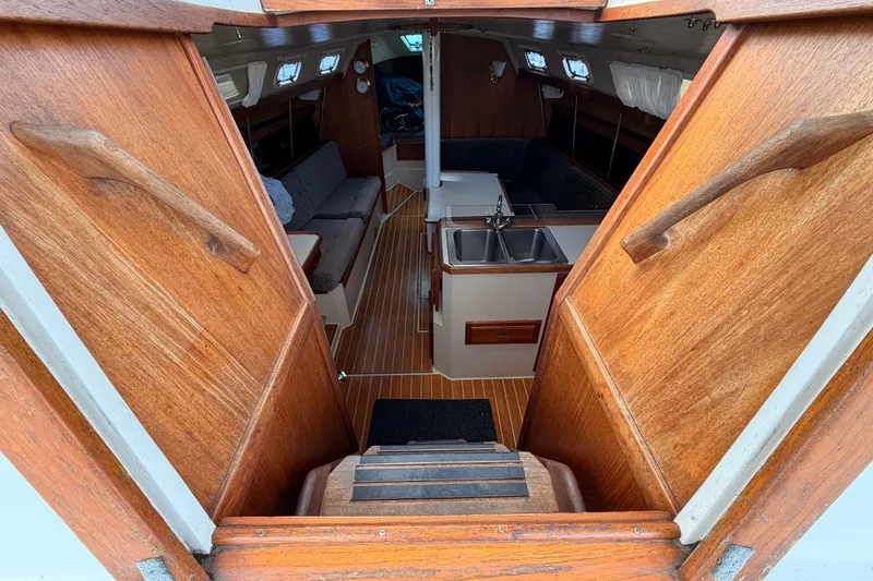 Slide: The Image of Interior view of 1989 Catalina 34 sailboat, featuring wooden cabinetry and compact kitchen area. - 21