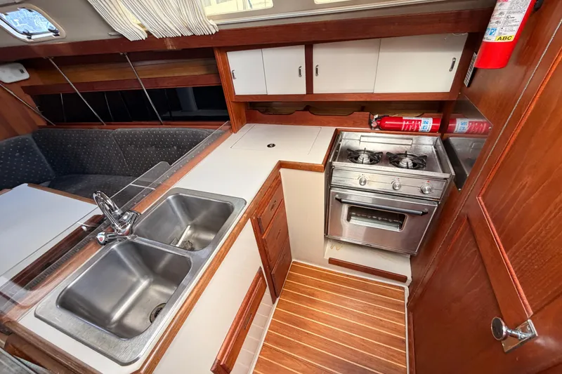 Slide: The Image of Compact kitchen in a 1989 Catalina 34 sailboat with stove, sink, and wooden cabinetry. - 29