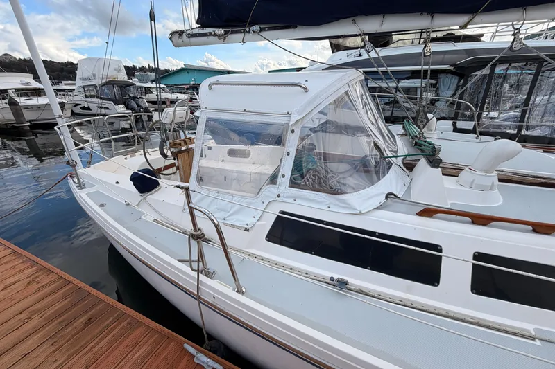 Slide: The Image of 1989 Catalina 34 sailboat docked at marina, featuring a covered cockpit and sleek design. - 6