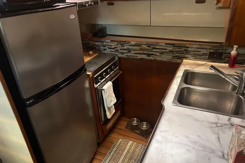 Slide: The Image of Compact kitchen in a 1980 Trojan F44 boat with modern appliances and dual sink. - 15