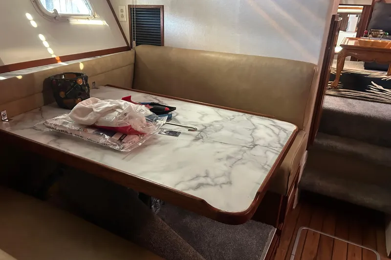 Slide: The Image of 1980 Trojan F44 yacht interior with marble table, beige seating, and stairs. - 5