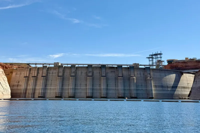 Slide: The Image of A large concrete dam with blue sky and calm water in the foreground. - 29