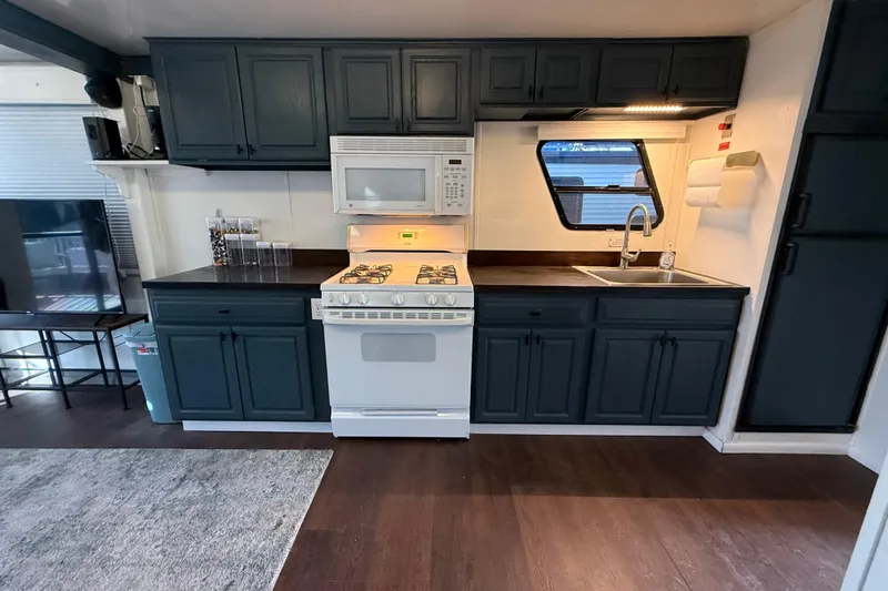 Slide: The Image of Modern RV kitchen with dark cabinets, white appliances, and wood flooring in 2006 Fun Country model. - 8