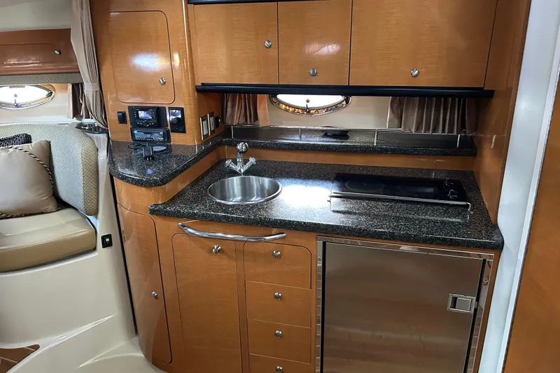 Slide: The Image of 2007 Chaparral 330 Signature yacht interior with kitchenette, featuring wood cabinets and granite countertop. - 12