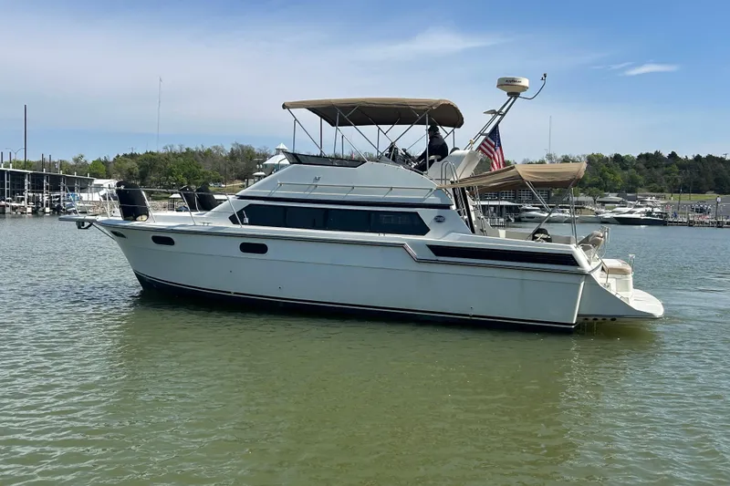 Slide: The Image of 1989 Carver 380 Santego yacht on calm water, with marina and trees in the background. - 26