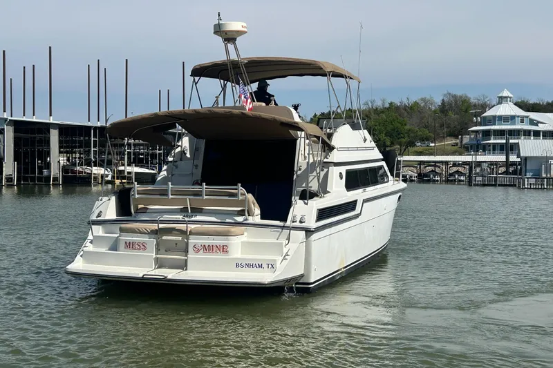 Slide: The Image of 1989 Carver 380 Santego boat docked at marina, rear view with canopy and American flag. - 31