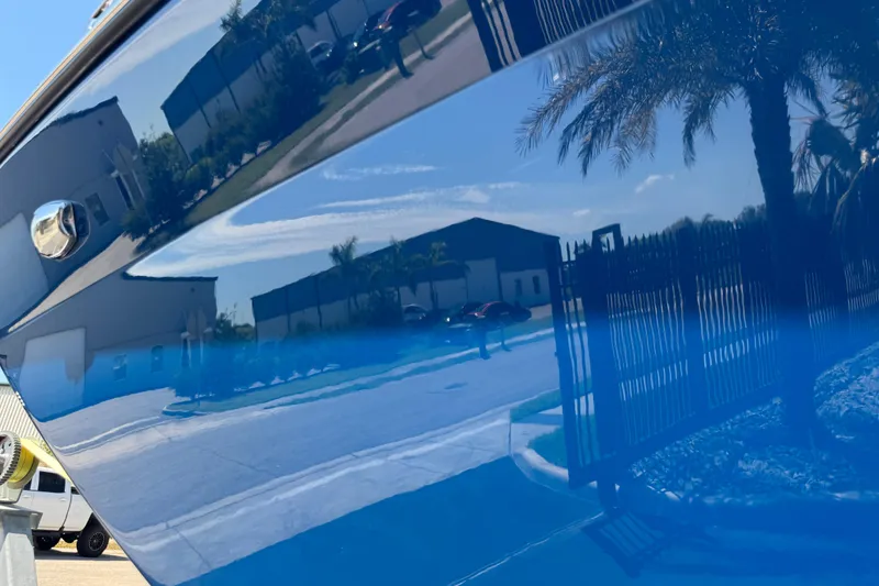 Slide: The Image of Reflection on blue hull of 2022 Scarab 285 ID boat, showing buildings and palm trees. - 101